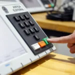 Teclado de urna eletrônica, com um dedo pressionando o botão verde de confirmação.