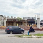 Obra do viaduto do Estação, com estruturas de concreto, pilares e veículos passando em frente.