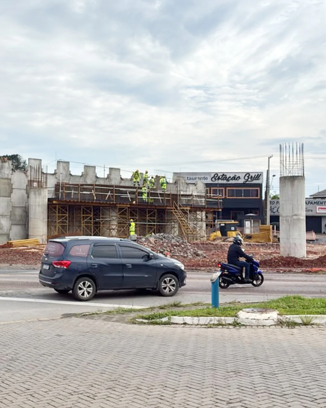 Obra do viaduto do Estação, com estruturas de concreto, pilares e veículos passando em frente.