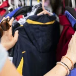 Mãos escolhem roupas penduradas em uma arara.