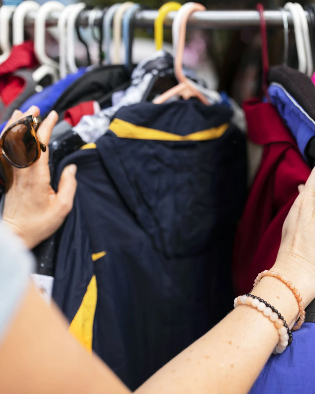 Mãos escolhem roupas penduradas em uma arara.