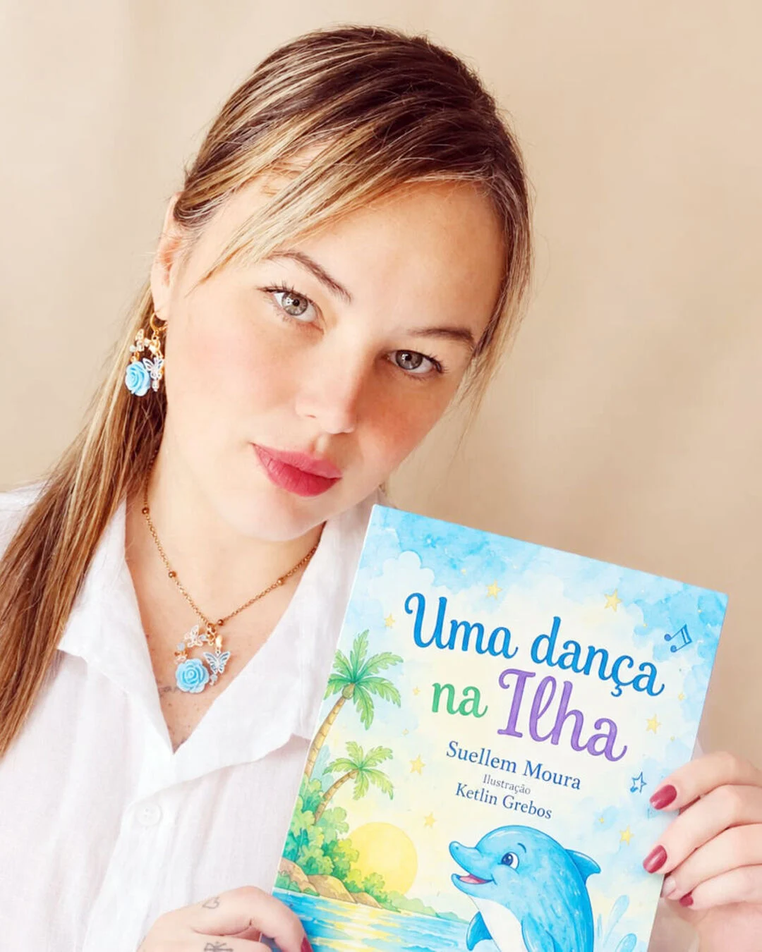 Mulher segura o livro infantil "Uma dança na Ilha", de Suellem Moura.