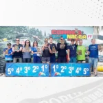 Atletas seguram troféus em pódio com colocações do 1º ao 5º lugar.